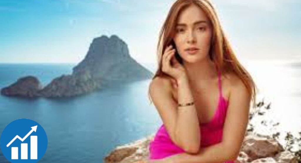   
Person in pink outfit posing near coastal rock formation under sunny blue sky.