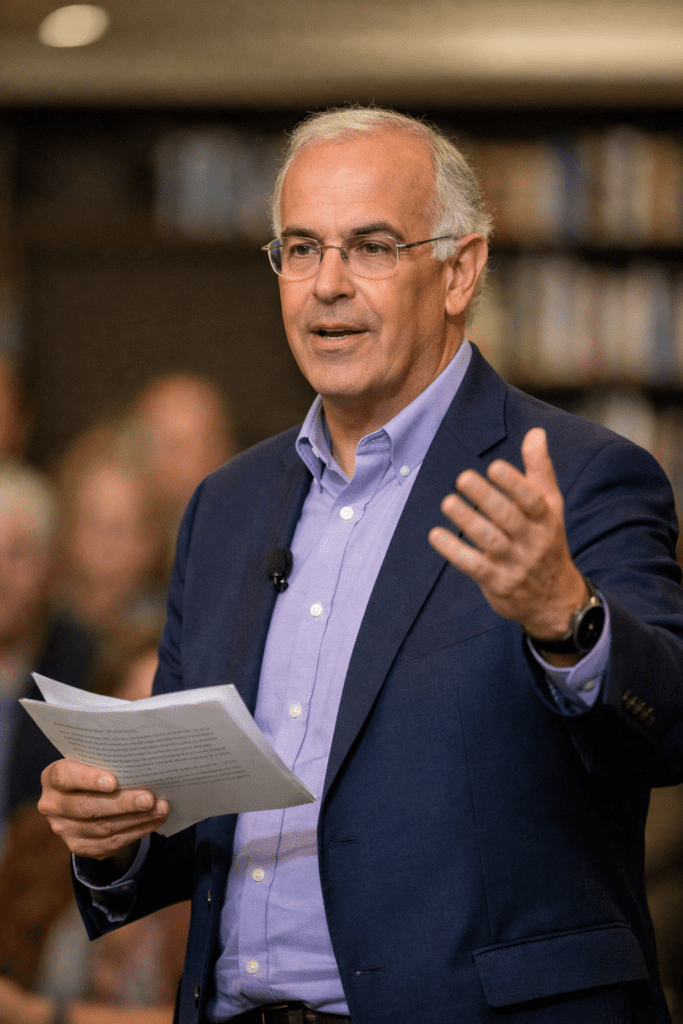 Alt Text: David Brooks speaking at a public event, delivering a lecture on culture and politics