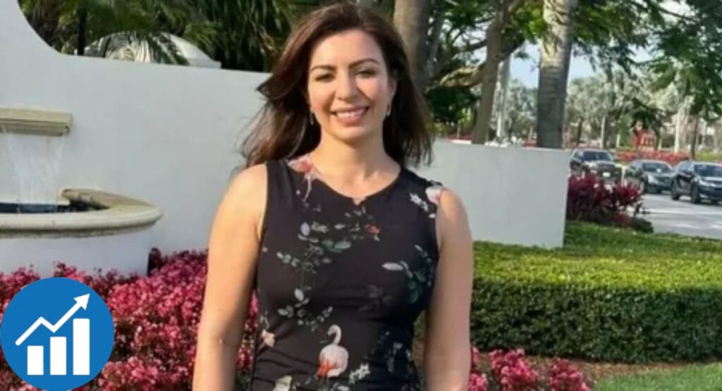 Woman in black flamingo-print dress standing outdoors near pink flowers and palm trees.
