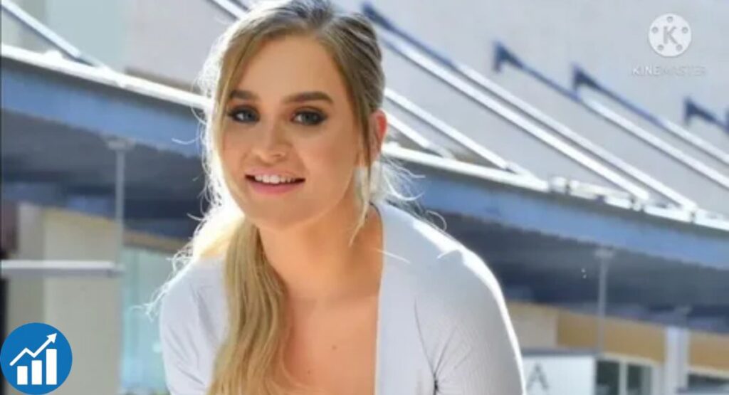 Blake Blossom outdoors in front of a modern building with angled beams and glass windows