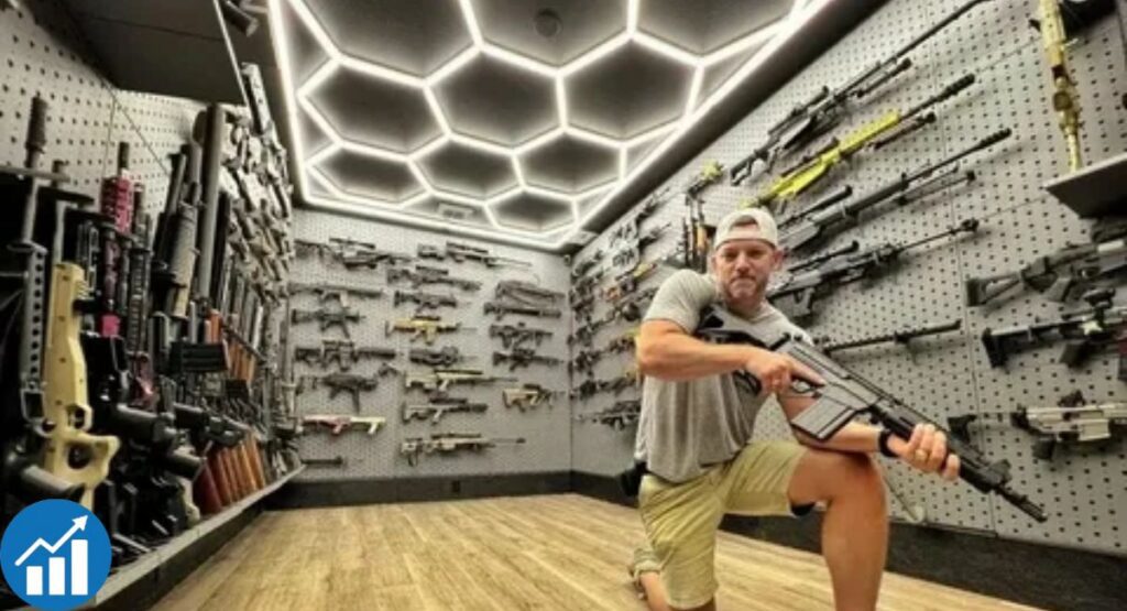 Man kneeling in a modern firearm room with rifles mounted on pegboard walls and LED ceiling lights.