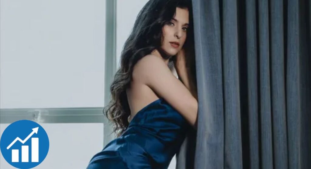 Leah Gotti styled in a dark satin dress, framed by natural light and subtle growth symbolism