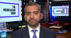 Mehdi Hasan seated in a television news studio during a political discussion in 2026
